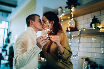 Beautiful couple kissing in kitchen with sparklers