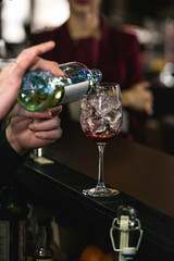 bartender making refreshing pink coctail with a rose on top isolated on a bar background
