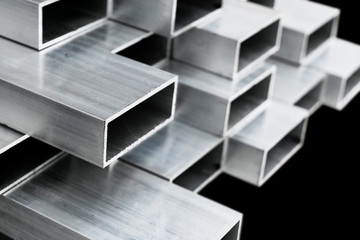 Aluminium profile for windows and doors manufacturing. Structural metal aluminium shapes. Aluminium profiles texture for constructions. Aluminum constructions factory background. - obrazy, fototapety, plakaty