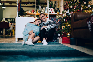 Happy young couple relaxing at decorated house on Christmas