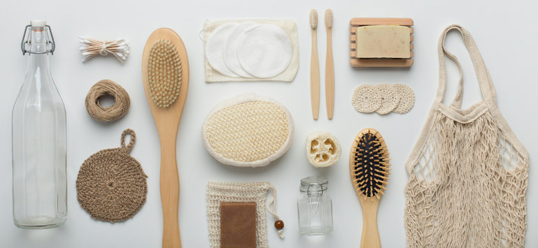 Flat lay of bamboo brushes, eco soap, reusable net bag and glass bottle