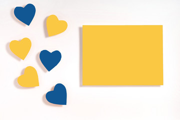 Valentine's day frame composition. Blue and yellow hearts blank sheet of paper on white background. Top view, flat lay, copy space