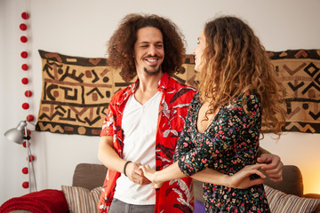 Attractive multicultural couple dancing in their living room.