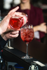 bartender making refreshing pink coctail with a rose on top isolated on a bar background
