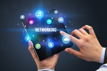 Businessman holding a foldable smartphone with NETWORKING inscription, social media concept