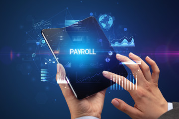 Businessman holding a foldable smartphone with PAYROLL inscription, successful business concept