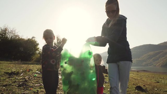 Young mother and her daughters carry a green bag full of trash counter light