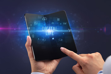 Businessman holding a foldable smartphone with DIGITAL LIFE inscription, cyber security concept