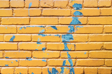Yellow brick wall with blue paint texture background. Old weathered and cracked bricks close up