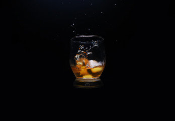 glass of whiskey and ice on black background