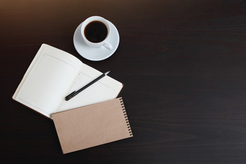 Spiral notebook and organizer on a dark table with a Cup of coffee. The view from the top. Copy...