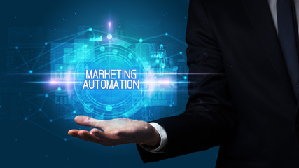 Man hand holding MARKETING AUTOMATION inscription, technology concept