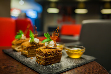 Delicious honey cake with salted caramel dripping from the top layer. Brown dessert with cream. Served in a white plate.