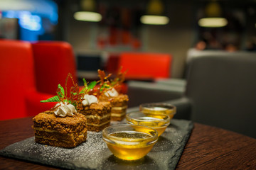Delicious honey cake with salted caramel dripping from the top layer. Brown dessert with cream. Served in a white plate.