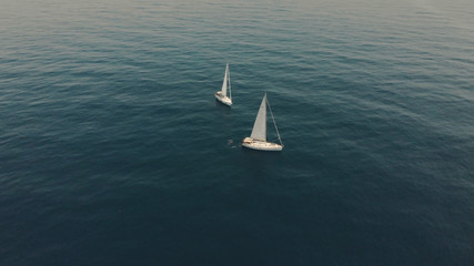 Aerial View of yacht in ocean. Drone footage of yachting around Balearic islands in the mediterranean sea. Silhouette of people