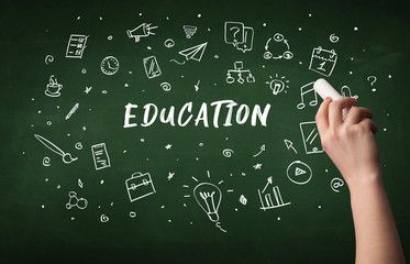 Hand drawing EDUCATION inscription with white chalk on blackboard, education concept