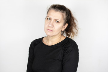 Beautiful middle-aged woman on a light background misses her youth, her hair starts to turn gray...