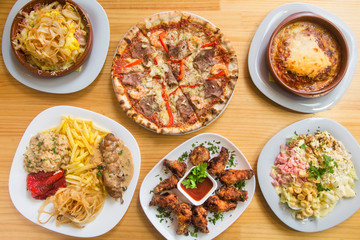 Fototapeta na wymiar Fast food composition top view, pizza, lasagna, chicken drumsticks, salad.