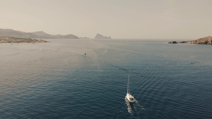 Aerial View of yacht near Ibiza, es Vedra and Vedranell islands. Drone footage of yachting in the Balearic islands. Very beautiful rocky islands. Unrecognizable people on yacht.