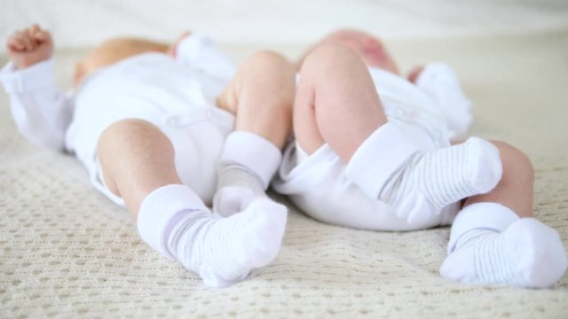 Close Up Of Newborn Baby Feet Of Twins In Socks.