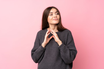 Young woman over isolated pink background scheming something