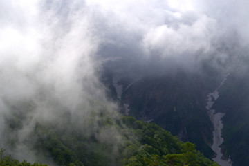 view from a mountain of swirling clouds over mountains