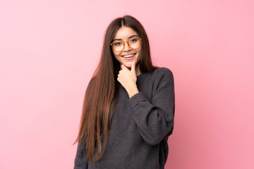 Fototapeta premium Young woman over isolated pink background with glasses and smiling