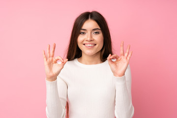 Young woman over isolated pink background showing an ok sign with fingers