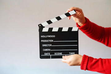 Woman dressed in red holding a black movie clapboard.