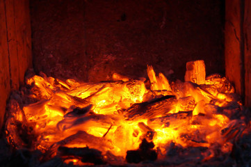 smoldering fire and flames from heat burnt logs.Wood is burned in the fireplace to make warm air in a house, when winter is coming.  P - obrazy, fototapety, plakaty