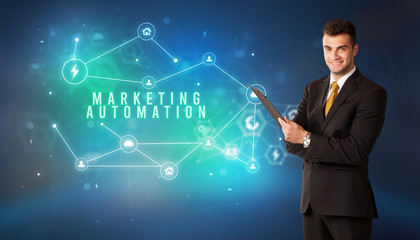 Businessman in front of cloud service icons with MARKETING AUTOMATION inscription, modern technology concept