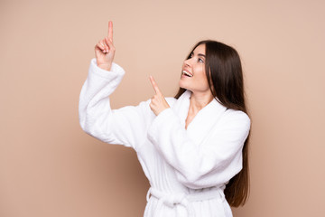 Young girl in a bathrobe over isolated background pointing with the index finger a great idea