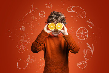 Elementary age kid having fun with oranges. Child with eyes covered with orange slices....