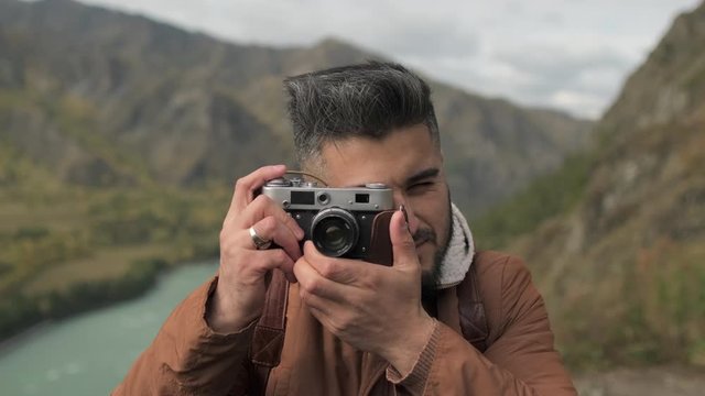 Portrait happy bearded attractive smiling young hiker tourist traveler man posing for camera and taking pictures by traveling on mountain. hiking travel tourism adventure landscape nature 4 K slowmo