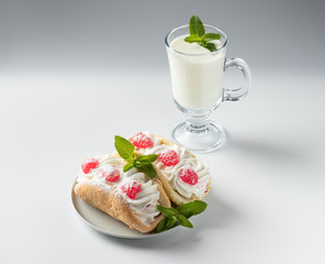 Kefir is decorated with a leaf of mint, a fermented drink. Air cake on a saucer on a white background