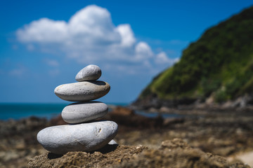 Zen rocks on foreground with a blurred landscape behind them