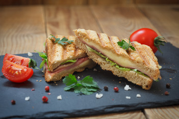 Close-up photo of a club sandwich. Toasted sandwiches with salami, lettuce and melted cheese on wooden background.