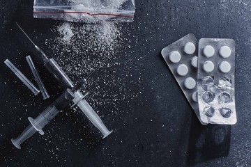 The concept of drug dependence, addiction. Scattered cocaine or heroin powder, syringes and blister...
