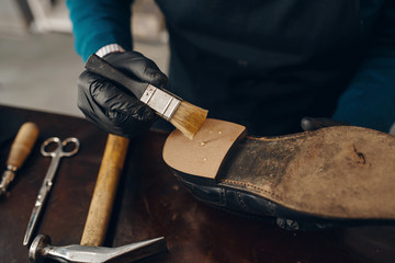 Shoemaker smears glue to the shoe, footwear repair