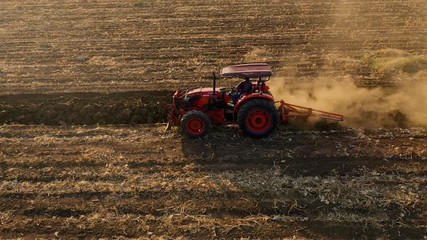 aerial view tractor cuts furrows in farm field for sowing farm tractor with rotary harrow plow preparing land for sowing. - Powered by Adobe