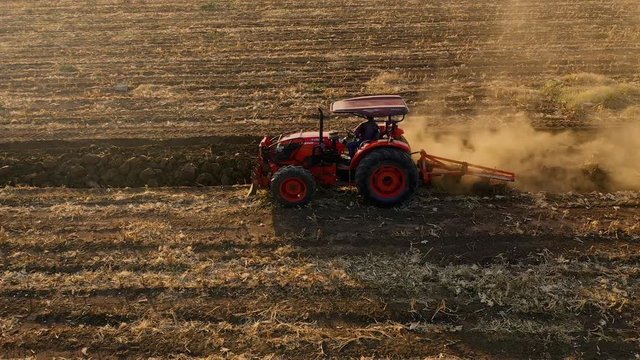 aerial view tractor cuts furrows in farm field for sowing farm tractor with rotary harrow plow preparing land for sowing.
