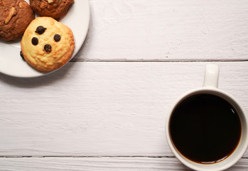 top view of a cup of hot americano or espresso coffee with chocolate chip and almond cookie on ceramic plate on white wooden background ,breakfast in minimal concept with copy space