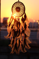 Silhouette of dream catcher with beautiful Sunrise and city view background. boho chic, ethnic amulet..