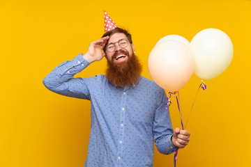 Redhead man with long beard holding balloons over isolated yellow background has realized something and intending the solution