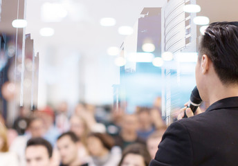 Speaker in meeting at business conference event. Seminar audience blurred in training room watch presentation. Presenter giving talk to people. City landscape double exposure.