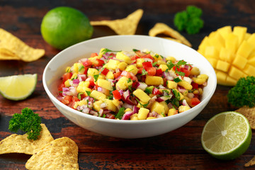 Bowl of fresh Mango Salsa with nachos chips and herbs. Healthy Vegan, Vegetables food.