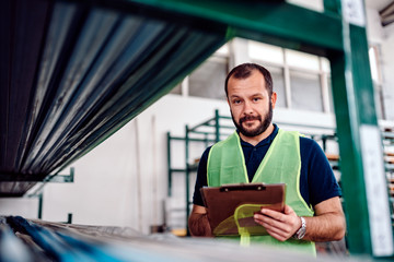 Stock clerk controlling warehouse inventory in the industrial factory