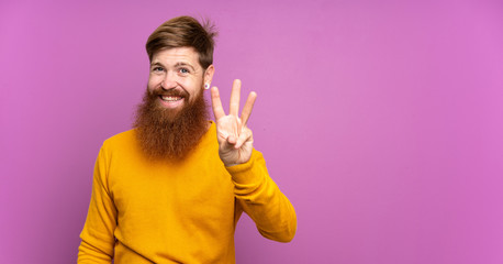 Redhead man with long beard over isolated purple background happy and counting three with fingers