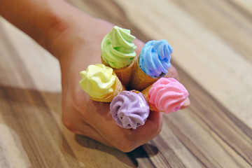 Colorful macaron in ice cream cone hold by Asian woman hand