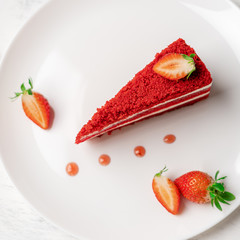 Red cake with fresh strawberries on a white plate top view close up.